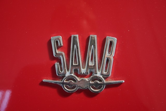 Appearing on Saab cars from 1963 the new Saab emblem was a sylised Saab aeroplane symbol with the letters S A A B in capitals across the top. This distinctive logo, signifying Saab's aircraft heritage, first appeared within the grid-pattern grille of the 1963 Saab 96. From 1967 onwards the logo, pictured (photographed from the bonnet of a Sonett II), appeared on the Sonett II and Sonett V4. The same badge was mounted above the boot handle on the Saab 96V4 until 1973/4.